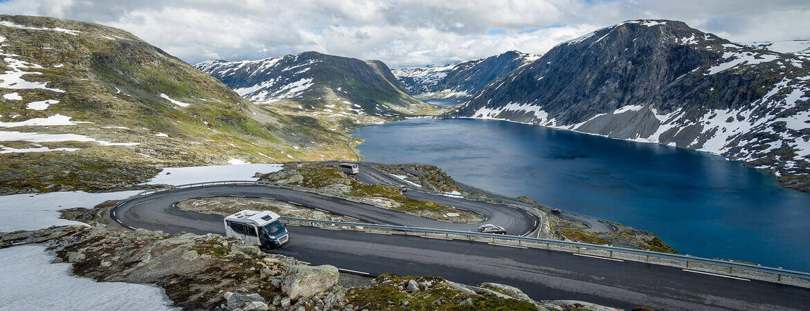 Wohnmobil fährt auf einer kurvigen Straße am Ufer des Geiranger-Fjords in Norwegen