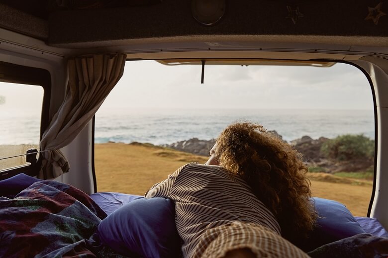 Frau im Camper schaut auf das Meer