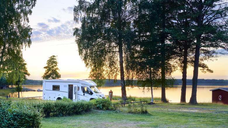 Camper auf einem Stellplatz an einem See in Schweden