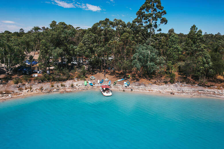 Boote und Camper an einem strahlend blauen See in Australien