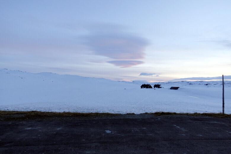 Schneelandschaft auf der norwegischen Riksvei 7 und Ferienhütten im Schnee