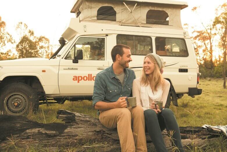 Pärchen sitzt vor einem Allrad Camper von Apollo