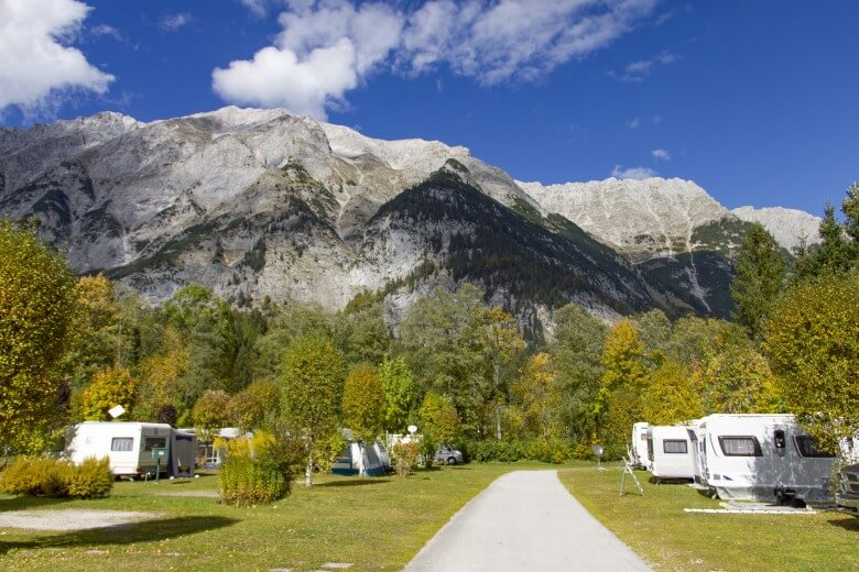 Wohnmobile stehen auf einem Campingplatz in Tirol und blicken auf die Berge