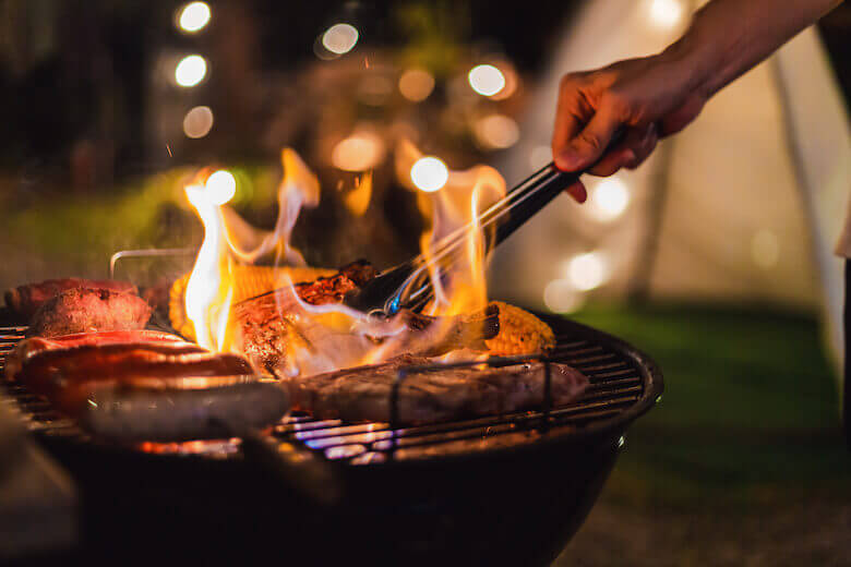 Im Urlaub sparen – Mann grillt auf dem Campingplatz.