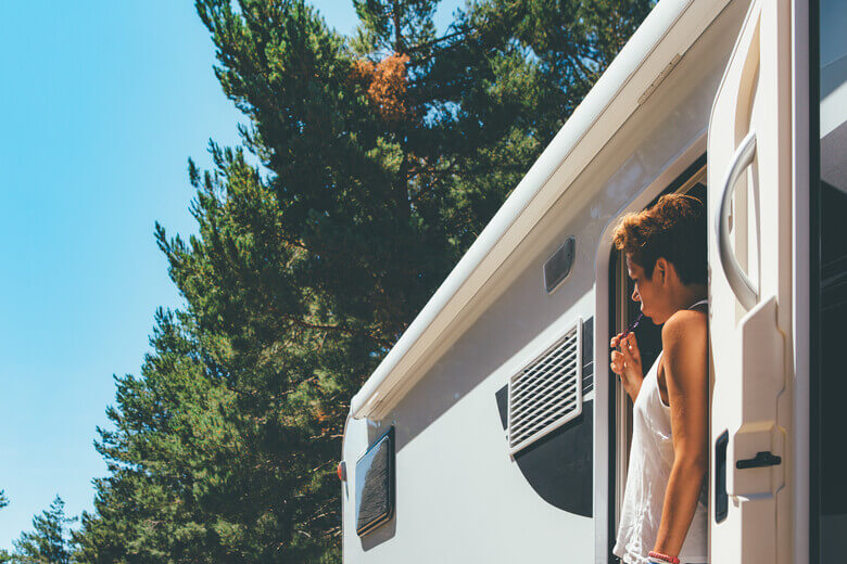 Frau putzt sich die Zähne im Camper