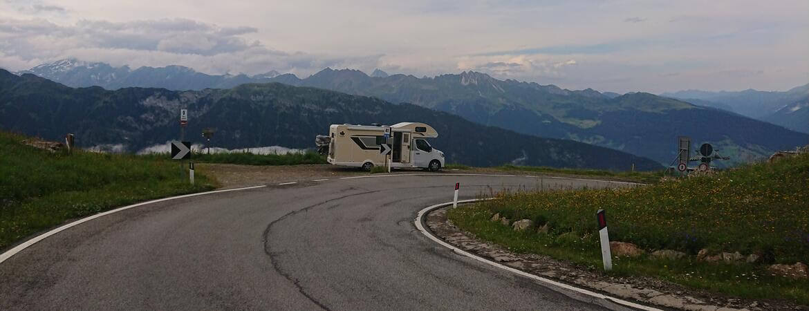 Camper am Straßenrand vor einem Alpenpanorama