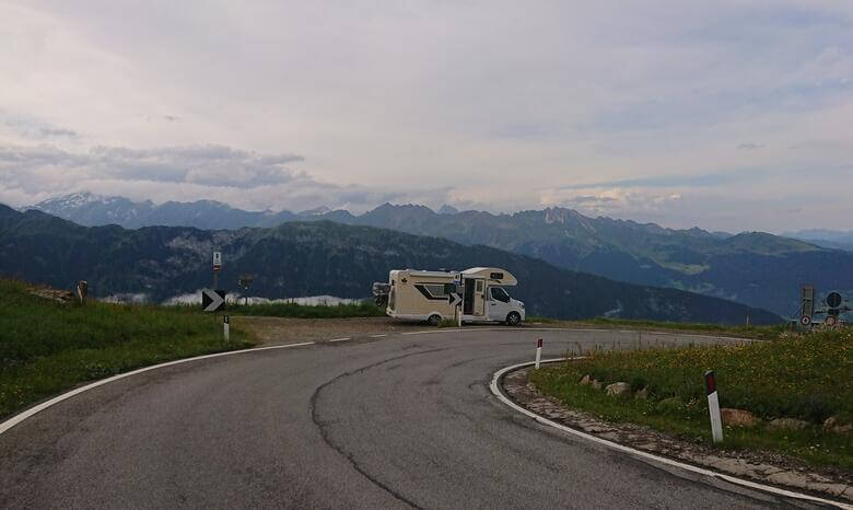 Camper am Straßenrand mit Alpenpanorama im Hintergrund