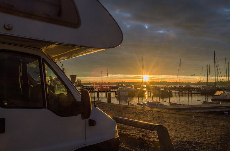 Wohnmobil steht im Hafen bei Sonnenuntergang.