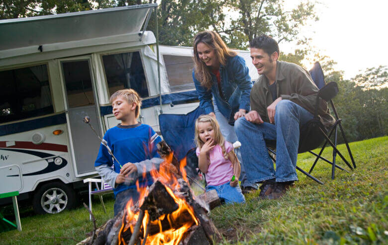 Familie grillt vor einem Wohnmobil