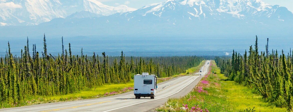 Wohnmobil fährt durch eine Berglandschaft in Alaska