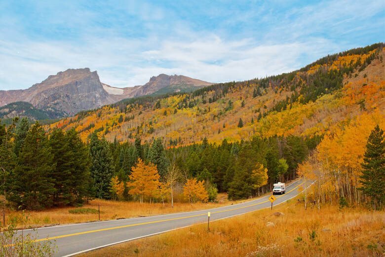 Wohnmobil fährt im Herbst durch die Berglandschaft der Rocky Mountains