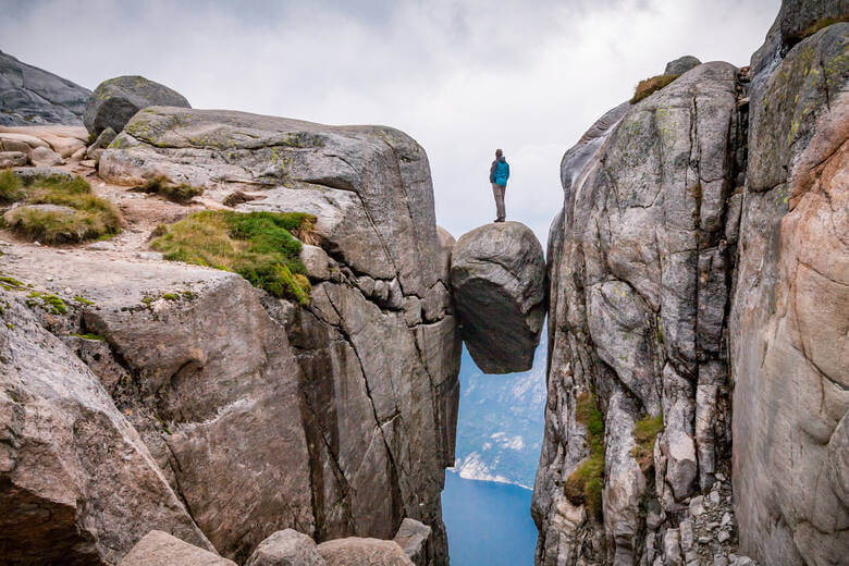 Mann auf Steinbrocken Kjergabolten in Norwegen