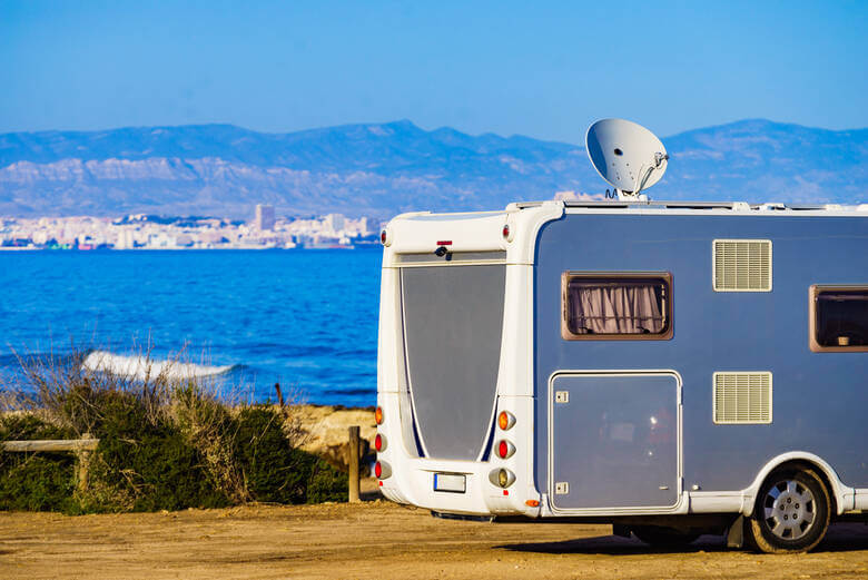 Wohnmobil mit Satellitenschüssel steht am Meer