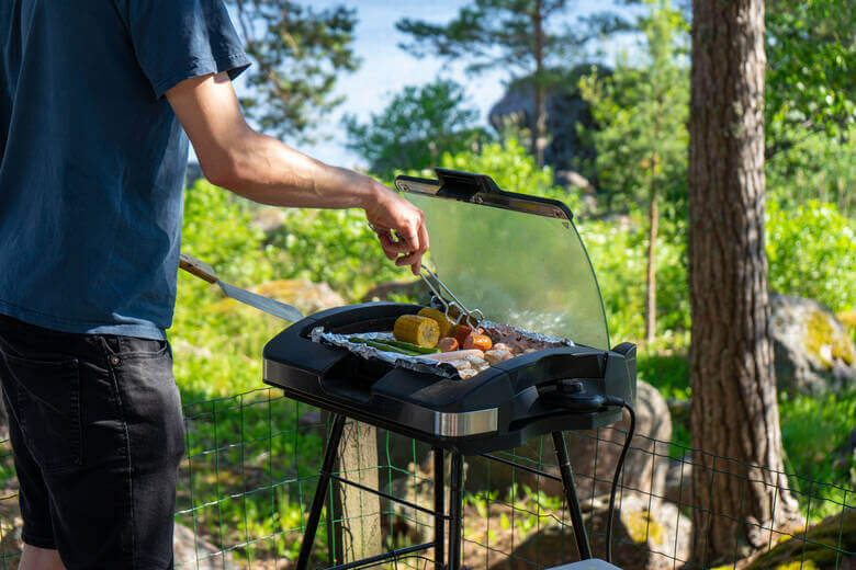 Mann grillt Gemüse und Fleisch in der Natur