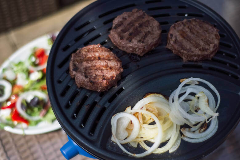 Tisch-Gasgrill mit Fleisch und Zwiebeln