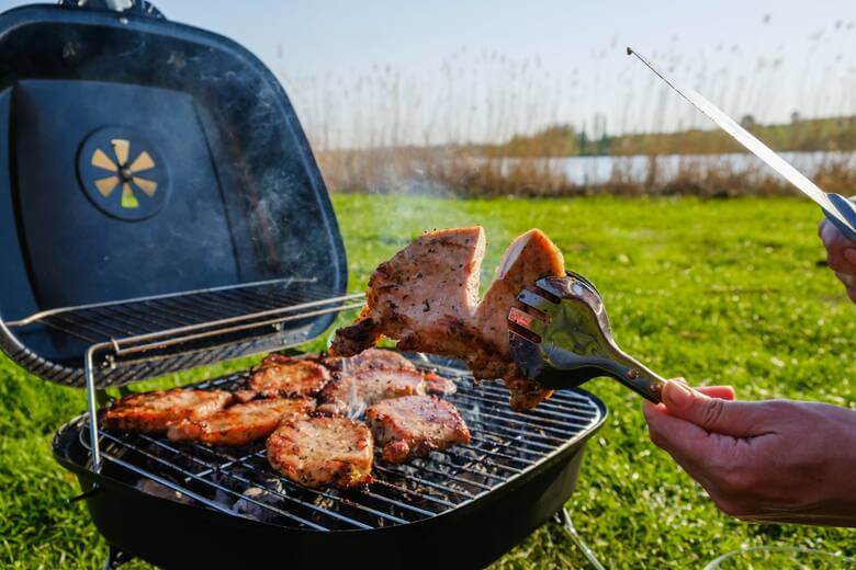 Person grillt in der Natur an einem See