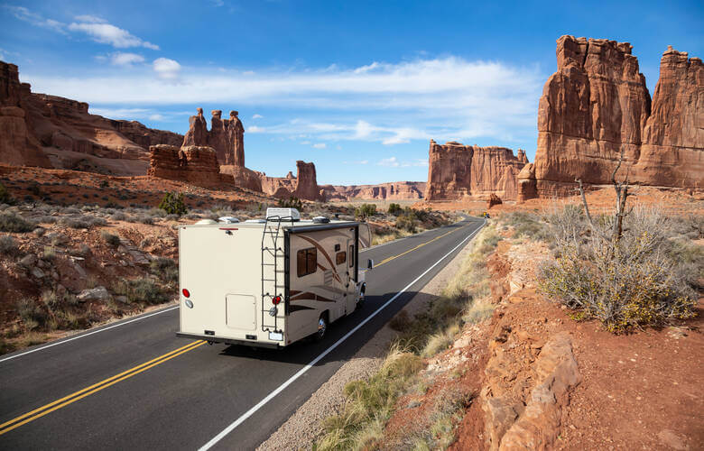 Wohnmobil fährt auf einer verlassenen Straße durch den Arches National Park in Utha