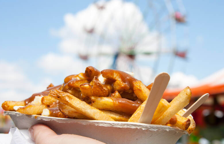 Eine Pappschachtel mit Poutine wird hochgehalten