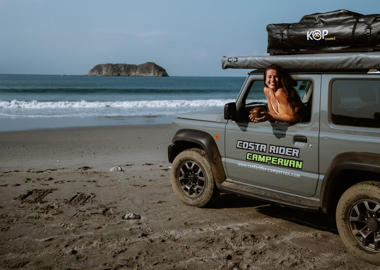 Lachende Frau in einem Camper in Costa Rica am Meer