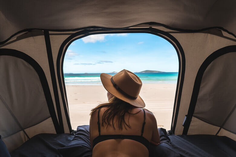 Frau wacht an einem Strand in Westaustralien im Zelt auf 