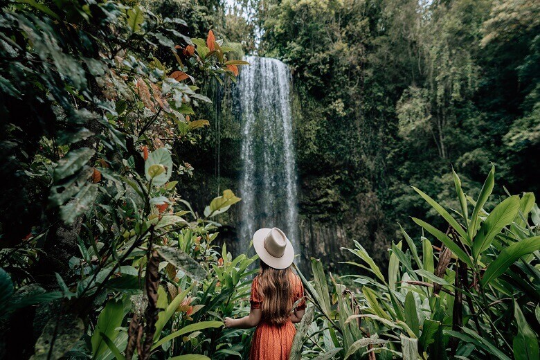 Frau steht vor einem Wasserfall im tropischen Australien