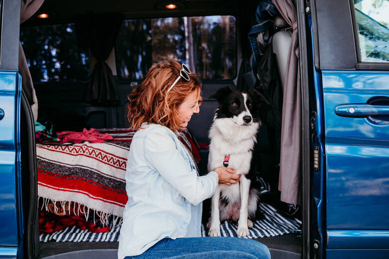 Frau sitzt mit Hund in einem Campervan