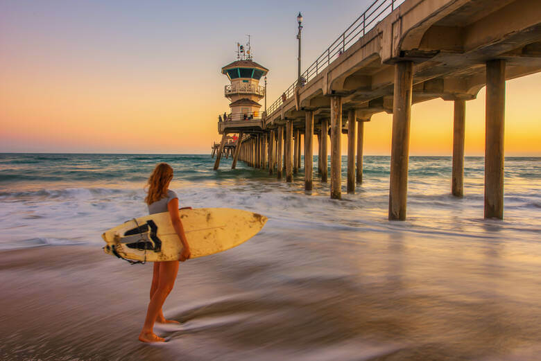 Junge Frau mit einem Surfbrett an einem kalifornischen Strand 
