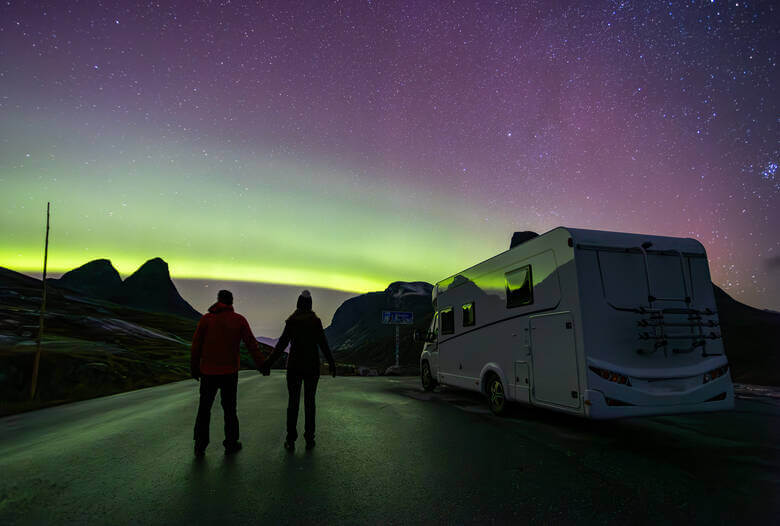 Pärchen und Camper vor den Polarlichtern in Skandinavien